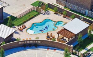 Outside on a sunny day, an aerial view shows the inground pool which features the airpark's logo on the bottom of the pool. 