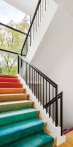 This multi-colored carpeted staircase, in pale rainbow hues, accented by a dark metal railing, shows the home owner's whimsical side. 