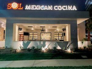 An exterior view of Mexican Cocina restaurant, at night, shows the stacking doors open and how it is a way to bring the outside in, and vice versa. 