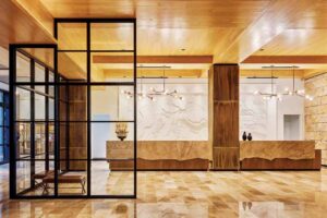 This shot of the lobby showcases the use of metal screens, marble floors and counters and elegant light fixtures above the reception desk. 