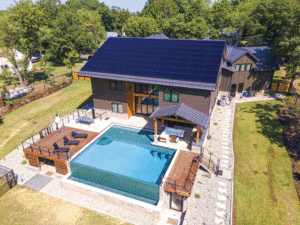 A view of a backyard with a pool, and the sloped roof featuring rail-less solar panels.