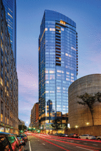A view of the high-rise at dusk, surrounded by other buildings.