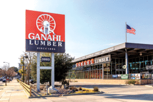 The exterior of Ganahl Lumber with a big sign out front featuring their white logo on an orange and brown background. 