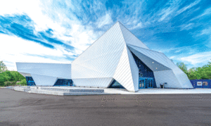 A modern, glossy, angled white building with a blue sky in the background.