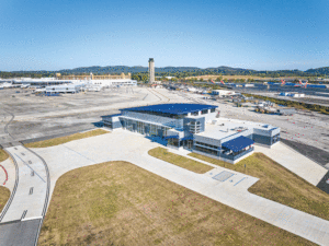 An aerial view of the building surrounded by a driveways and runways and control tower in the far background.