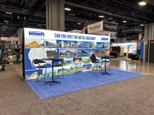 The Metal Building Manufacturers Association booth at the 2024 AIA conference. The backdrop shows the company logo across the top and multiple photos of metal buildings.