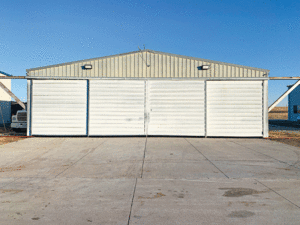 A beige colored airplane hangar looks old and in need of a refresh. 