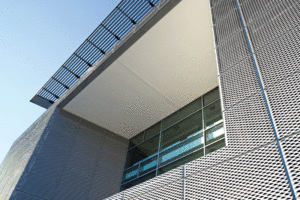 An angled, close up view of a window, and the panels around it are mesh metal. 