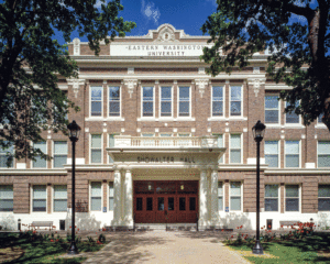 A horizontal view of the entrance way of a light colored stone building. Windows are trimmed in white aluminum. 
