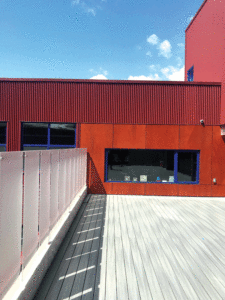 An exterior of the second storey shows the orange/brown panelling, a horizontal window trimmed in blue, and a fenced-in balcony area.