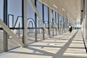 Metal mesh encloses a pedestrian walkway, providing a view of the outdoors. 