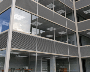 Offices in an office building shown through the windows on the exterior. 