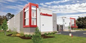 This storage facility features, white panels, red trim and the Cube Smart logo in red.