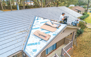 A worker sits on top of a roof where is installing insulation.