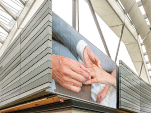 A close-up shot of a facade featuring a man's hands putting a wedding ring on a women's hand.