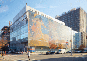 The Harlem Hospital from the street corner view. One side of the building is taken up with a mural featuring jazz musicians in yellow and orange tones.