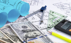 A blueprint of an architect with money calculator. symbolic photo for financing and planning of a new house. Blueprints rolls and a drawing instruments on the worktable