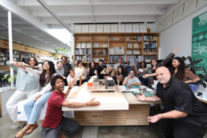 A group of people surround a boardroom table, smiling for the camera.