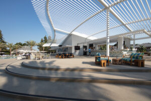 A horizontal view of a patio is covered with a white metal canopy-like structure with open slats.