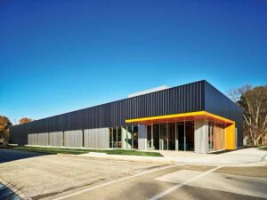 A one-story, rectangular building with black panels on the top half and light grey on the bottom half. 