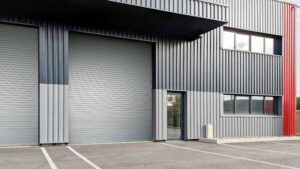 A single grey rolling door on the exterior of a grey, metal-panelled building.