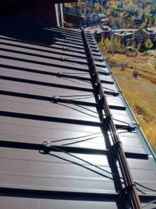 A vertical look at a brown metal roof with snow guards in place.