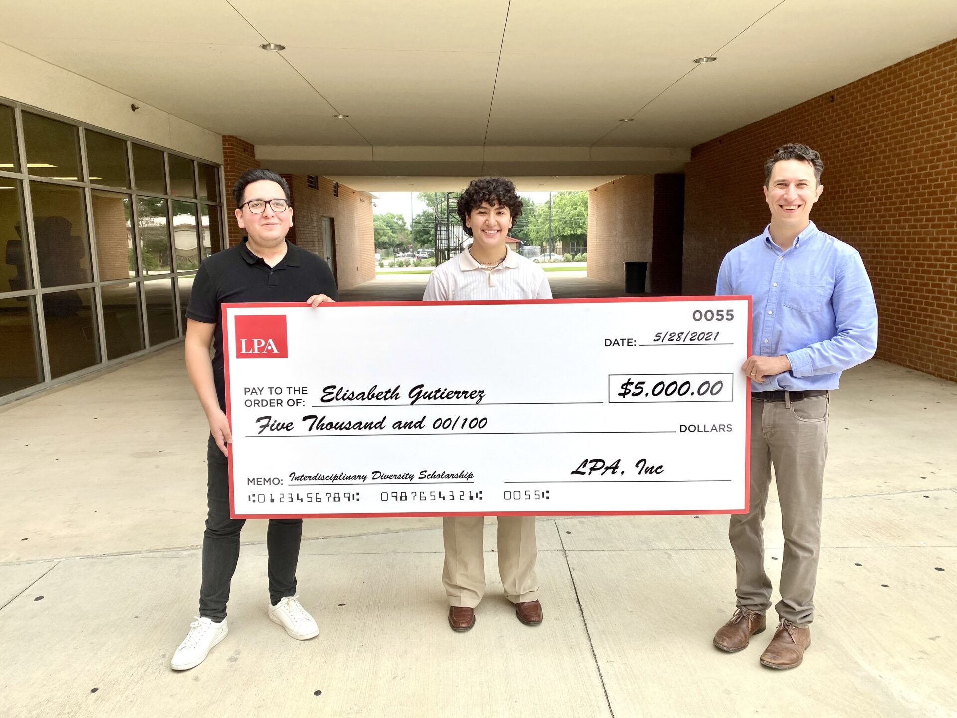 Three people hold a prop cheque worth $5000.