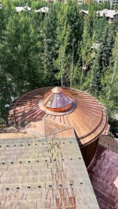 A unique spiral feature sits on top of the round, copper roof on a home.