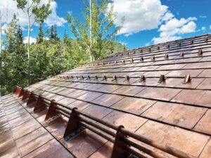 A close up view of a copper paneled roof with a snow horizontal snow guards. 