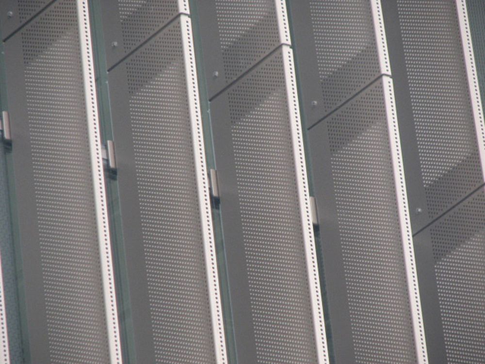 A close-up of perforated metal shading panels attached to the outside of a college building.