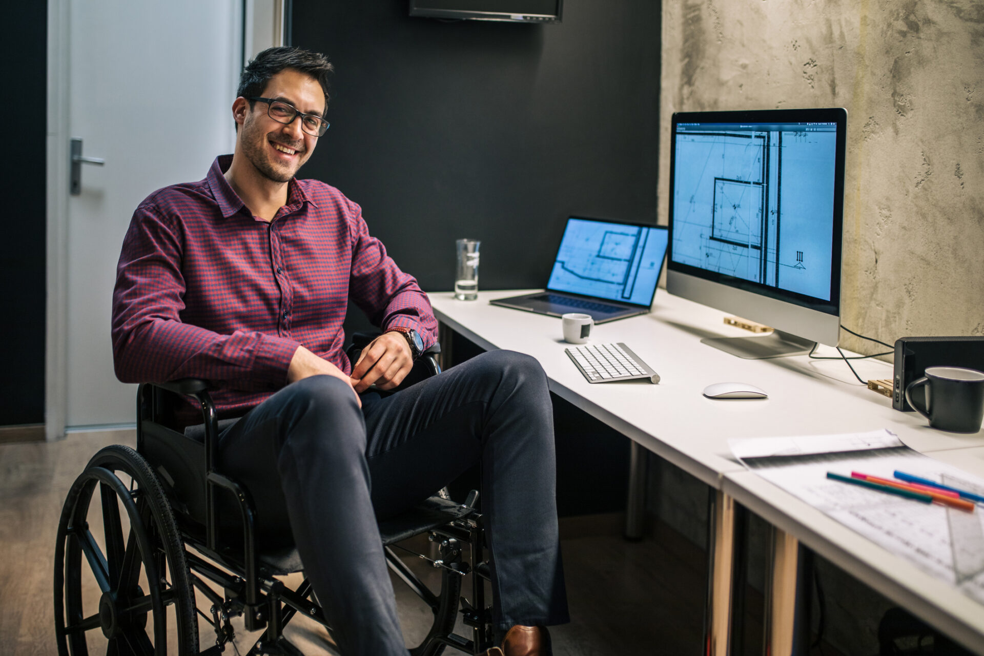 An architect with differing abilities working in the office while sitting in his wheelchair