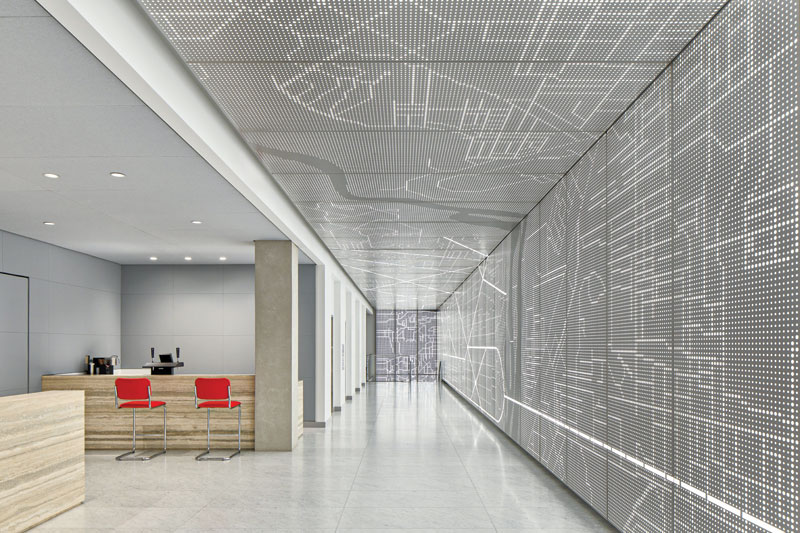A long office hallway with panels containing LED lights lit up with the image of a roadmap of Washington, D.C.. To the left is a sitting area with four chairs.