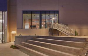 Outdoor stairs in front of a window displaying a dinosaur skeleton.