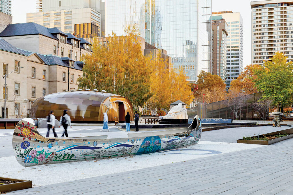 Public memorial at Nathan Phillips Square in Toronto featuring a Teaching Lodge and engraved sculpture with brass and wood detailing.