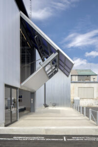 Large translucent bifold door partially open on the ICA Watershed building, creating a canopy effect above the concrete entryway.