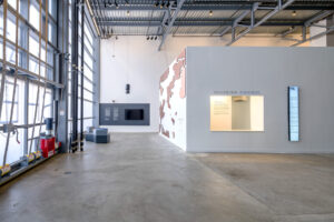 Interior of the ICA Watershed showing exposed steel framing, polished concrete floors, and a white gallery structure under natural daylight.