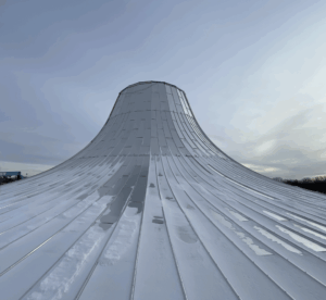 Roof view of sleek metal panels with reflective quality and upward curve.