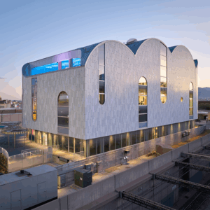 Distant side view of the 2025 MCA Design Awards' best overall building, a grey building with intricate roof curves mimicking the appearance of a cloud.