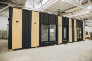 Modern prefabricated tiny house being built inside a spacious factory, showcasing innovative construction techniques and sustainable housing solutions.
