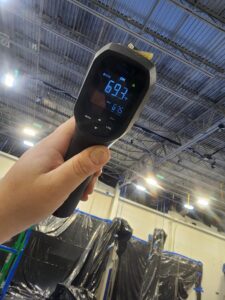 Image of a digital laser thermometer in front of a metal ceiling.