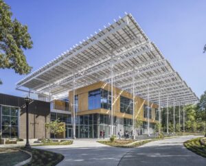 Exterior image of a structure. Roof made of white panels extends well beyond structure walls, offering shade to the surrounding area.