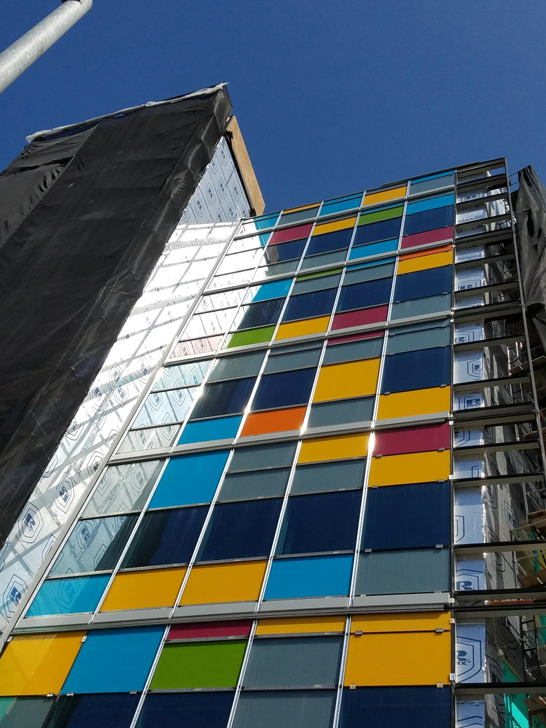 Upward angle of building exterior featuring rainscreens with polyiso CI. Various colors appear on building segments offering an eclectic and bright aesthetic.