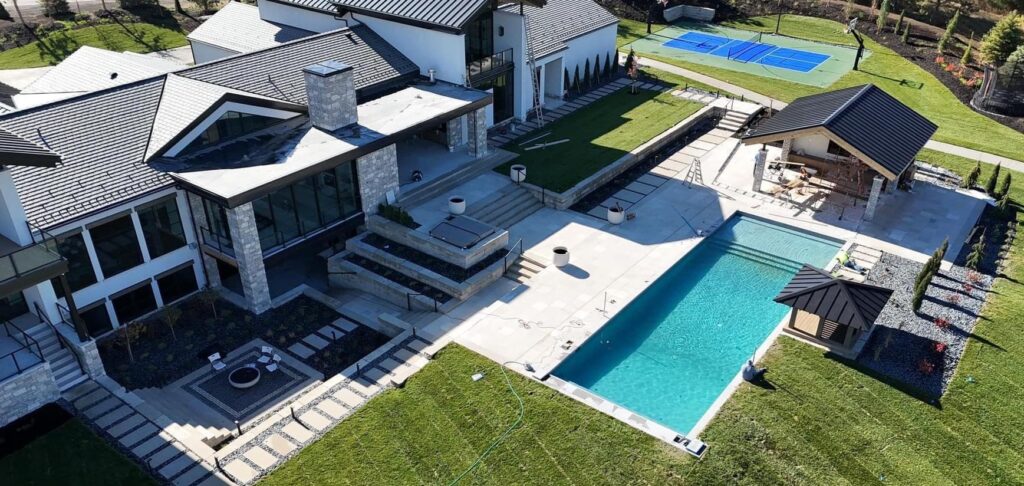 Overhead view of sizable property featuring a pool, and home with a slate grey roof.