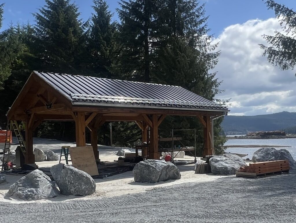 Metal shaded canopy shown with metal panel roof, lined with snow guards. Environment includes vast trees and natural waterfront.