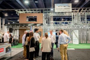 A large steel framing structure is in the background of show participants speaking together.