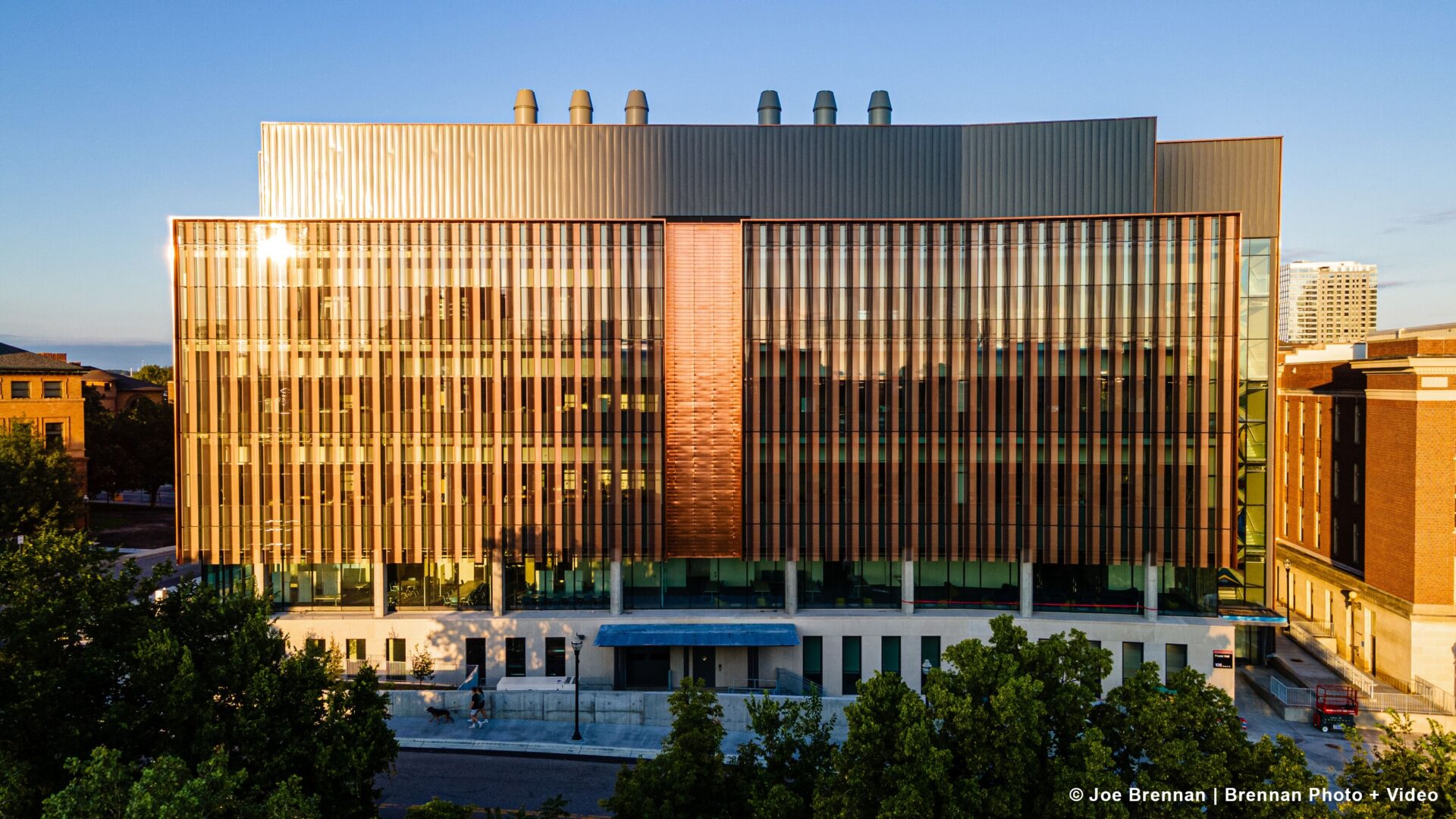 Front-facing view of the building with the sun shining off the architectural metals. The photograph was captured at dusk.