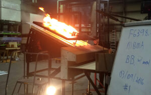 Flames atop a metal panel in a testing process.