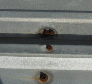 Rest on fasteners on a corrugated metal roofing panel.
