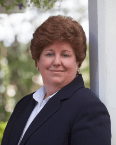 Outdoor headshot of architect Deborah Costantini, photographed in a suit.