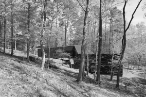 Black and white photo of elevated level of a nature-surrounded home.